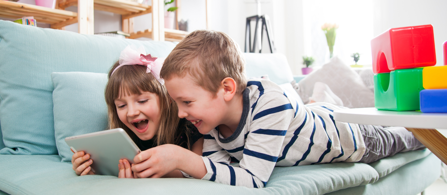 Sibling laughing while learning on their tablet