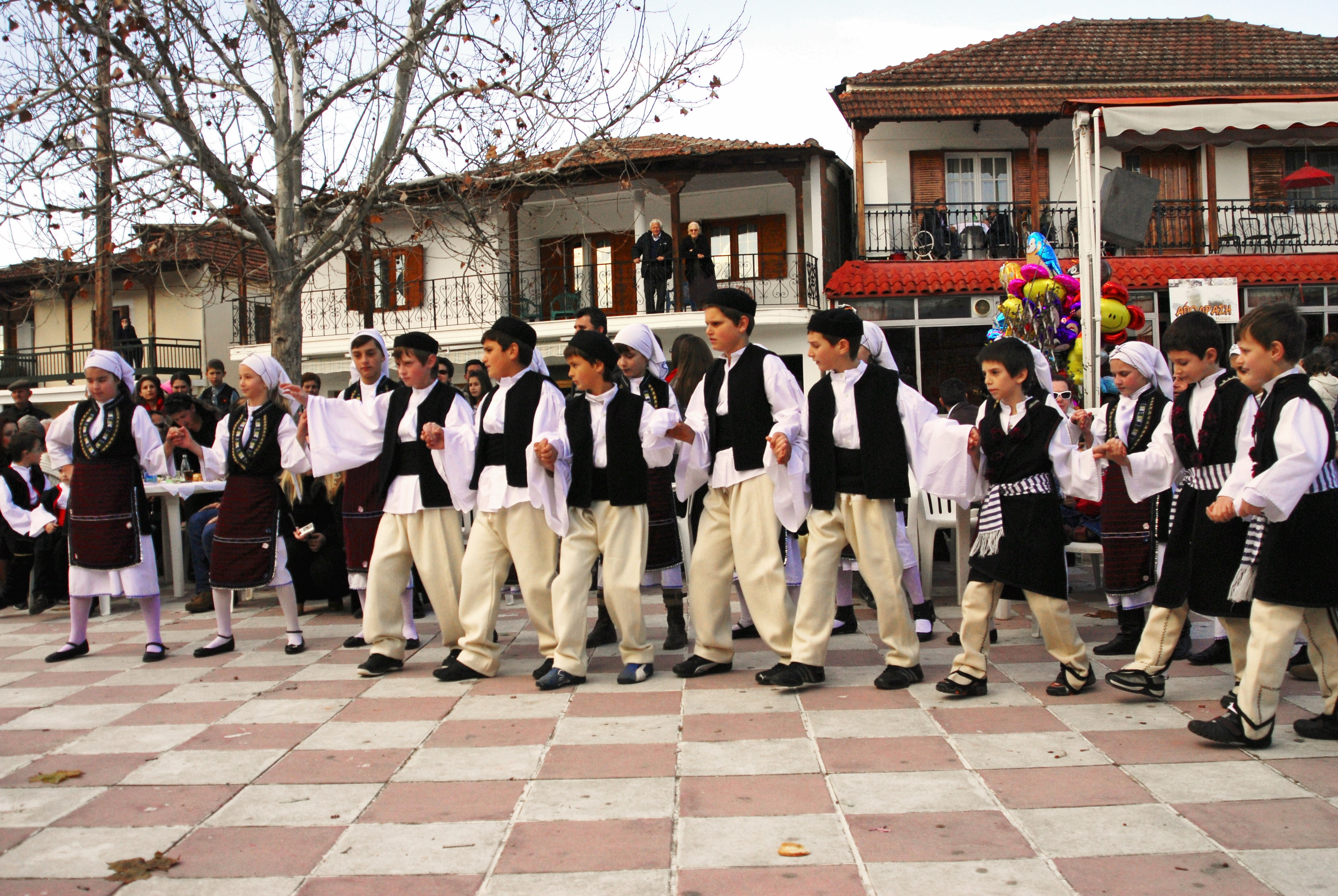 School kids dancing a traditional Greek dance on the square of a Greek village, wearing traditional clothing